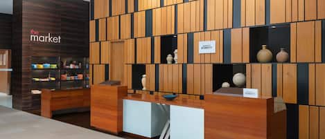 Un mostrador de recepción con diseño de panel de madera, un letrero que dice 'The Market' y un letrero de 'Marriott Bonvoy'.