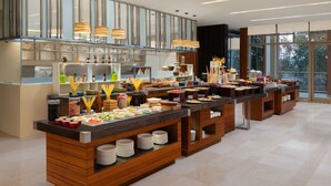 Ein reichhaltiges Buffet mit verschiedenen Speisen und Beilagen, Holztresen und hängenden Pendelleuchten.