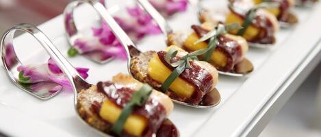 A row of dessert spoons with fruit and chocolate on a white tray.