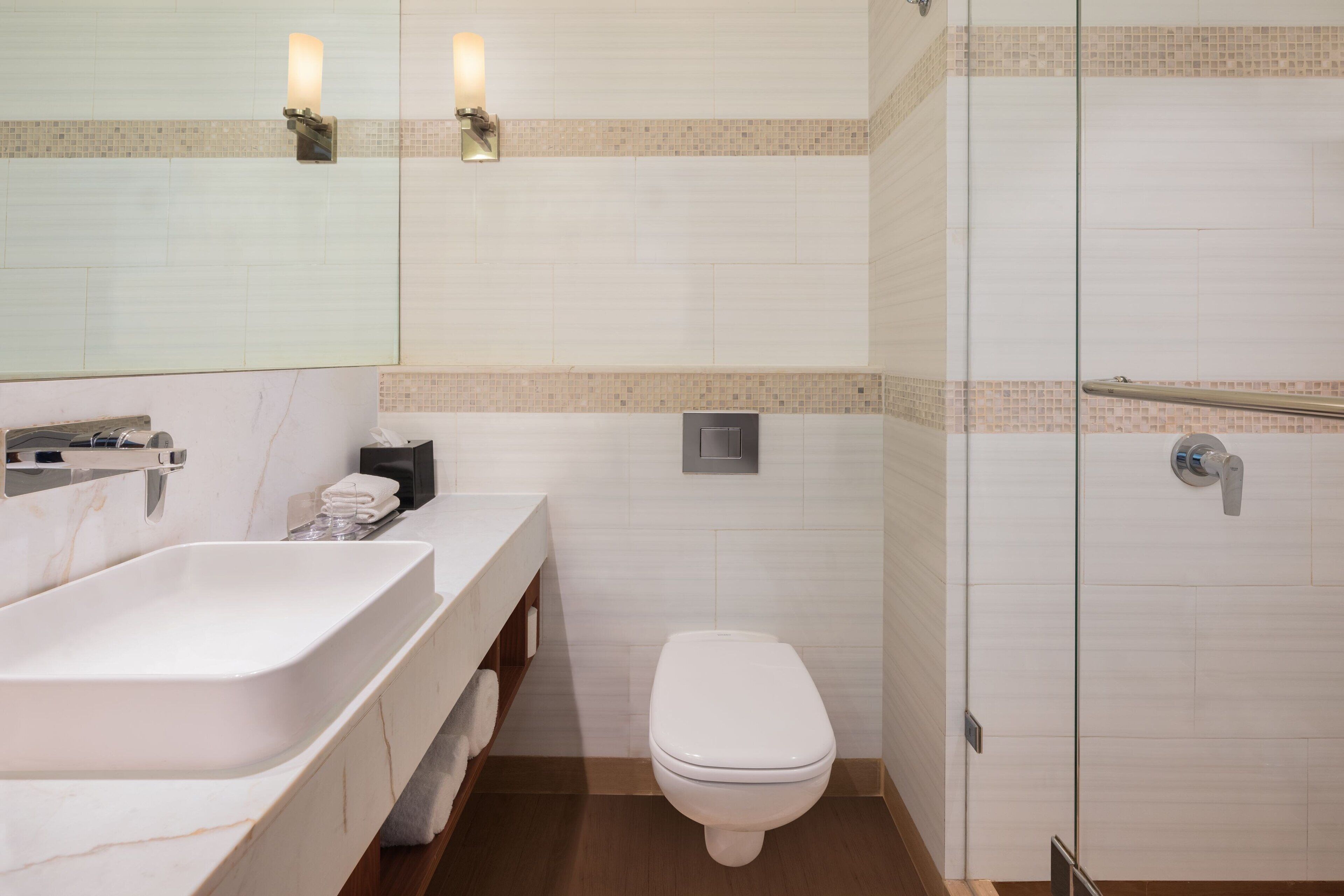 Une salle de bain moderne avec un grand lavabo blanc, des toilettes et une douche à parois de verre.