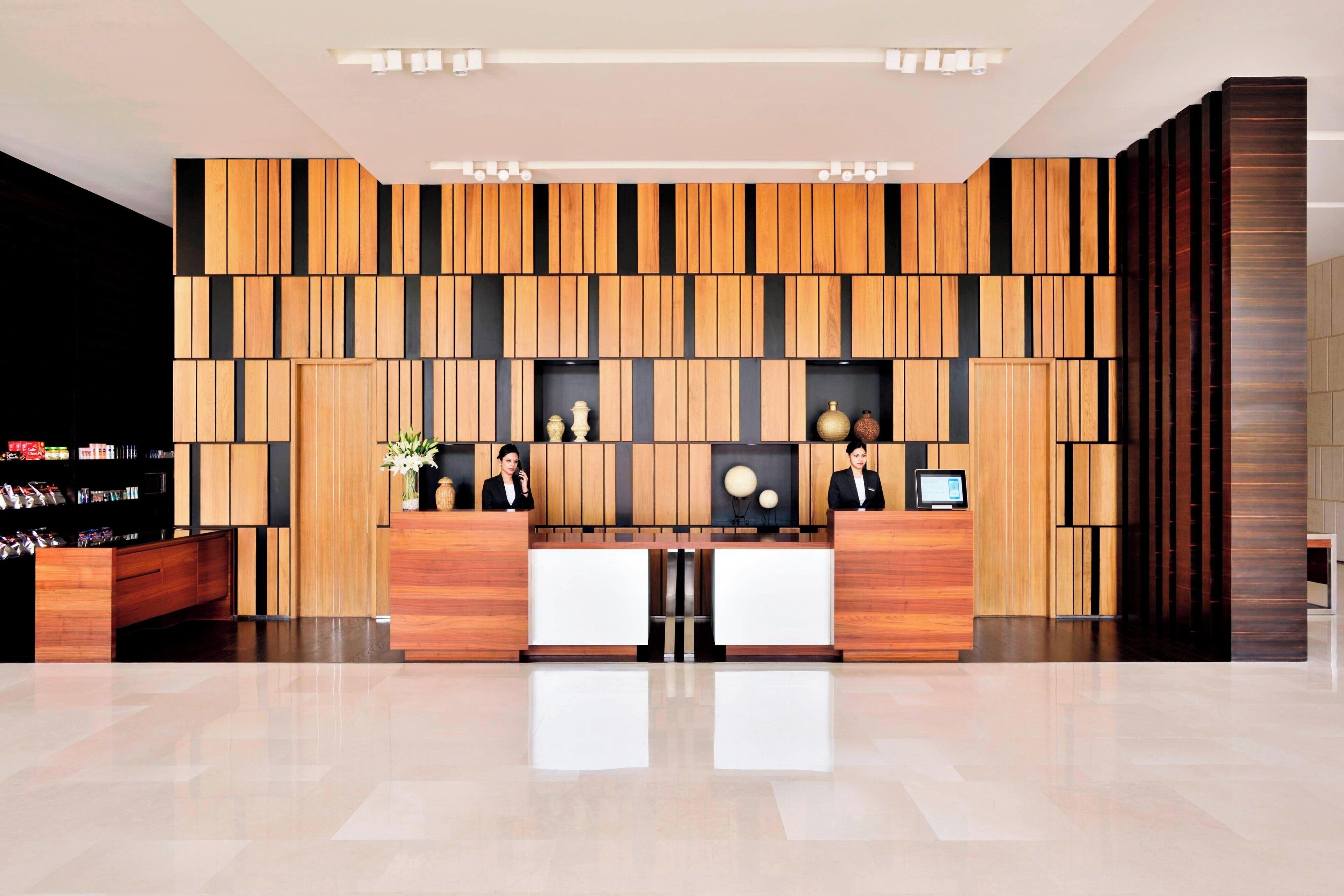 Un área de recepción moderna con paneles de madera, un mostrador de recepción y una exhibición de servicios.