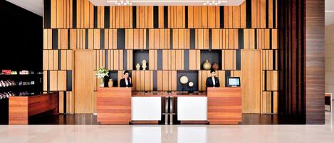 A modern reception area with wooden paneling, a reception desk, and a display of amenities.