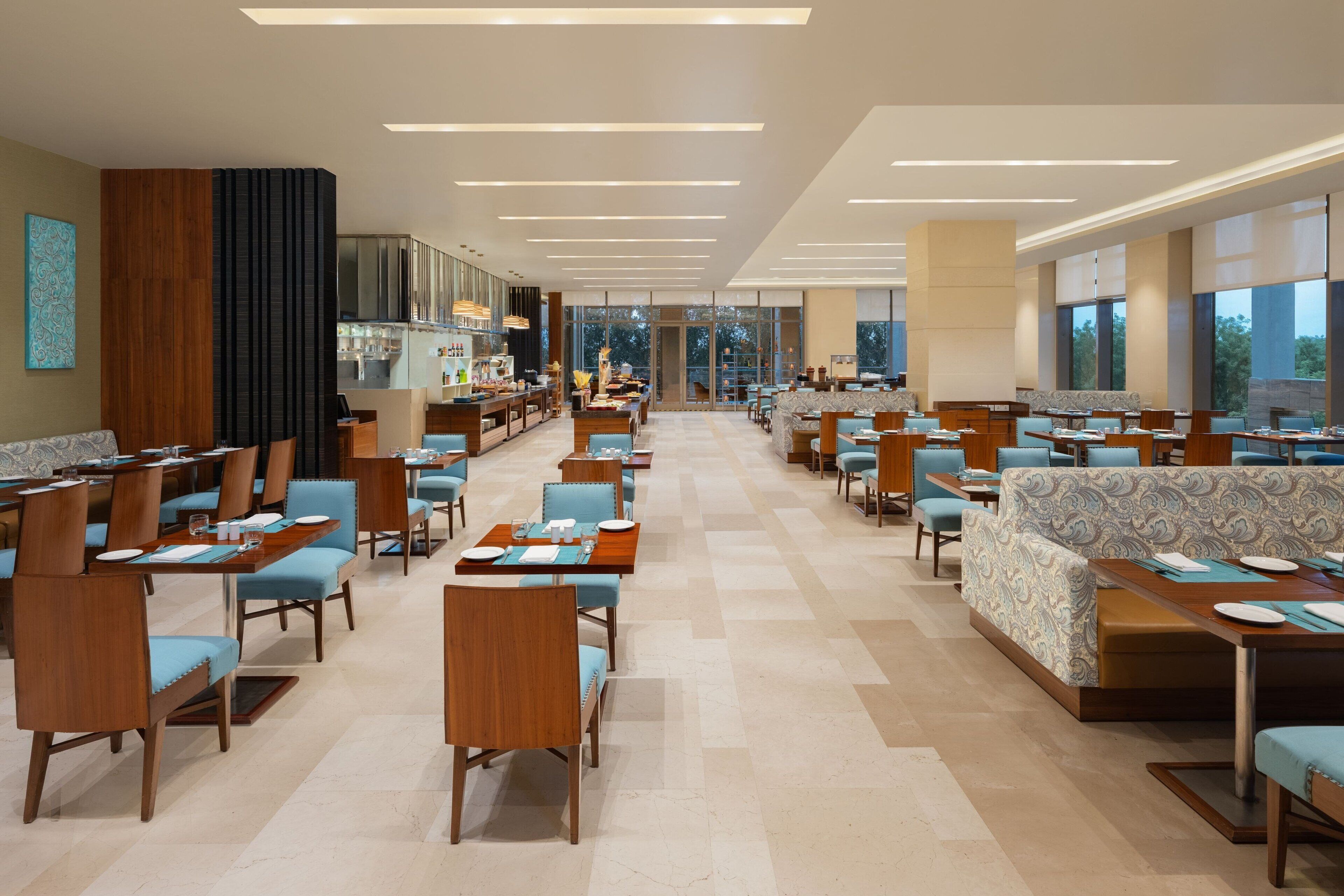 A spacious hotel lobby with multiple dining areas, including booths and tables, and a bar area with a counter.