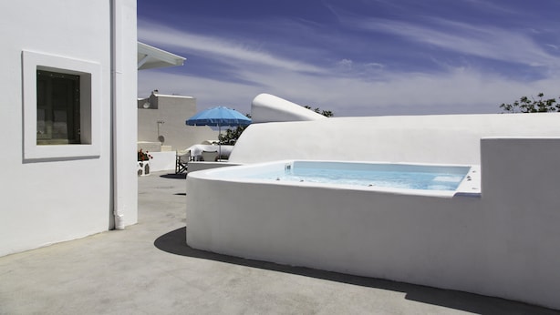 A modern white building with a swimming pool, a blue umbrella, and a clear sky. - Ayoba Santorini (Santorini)