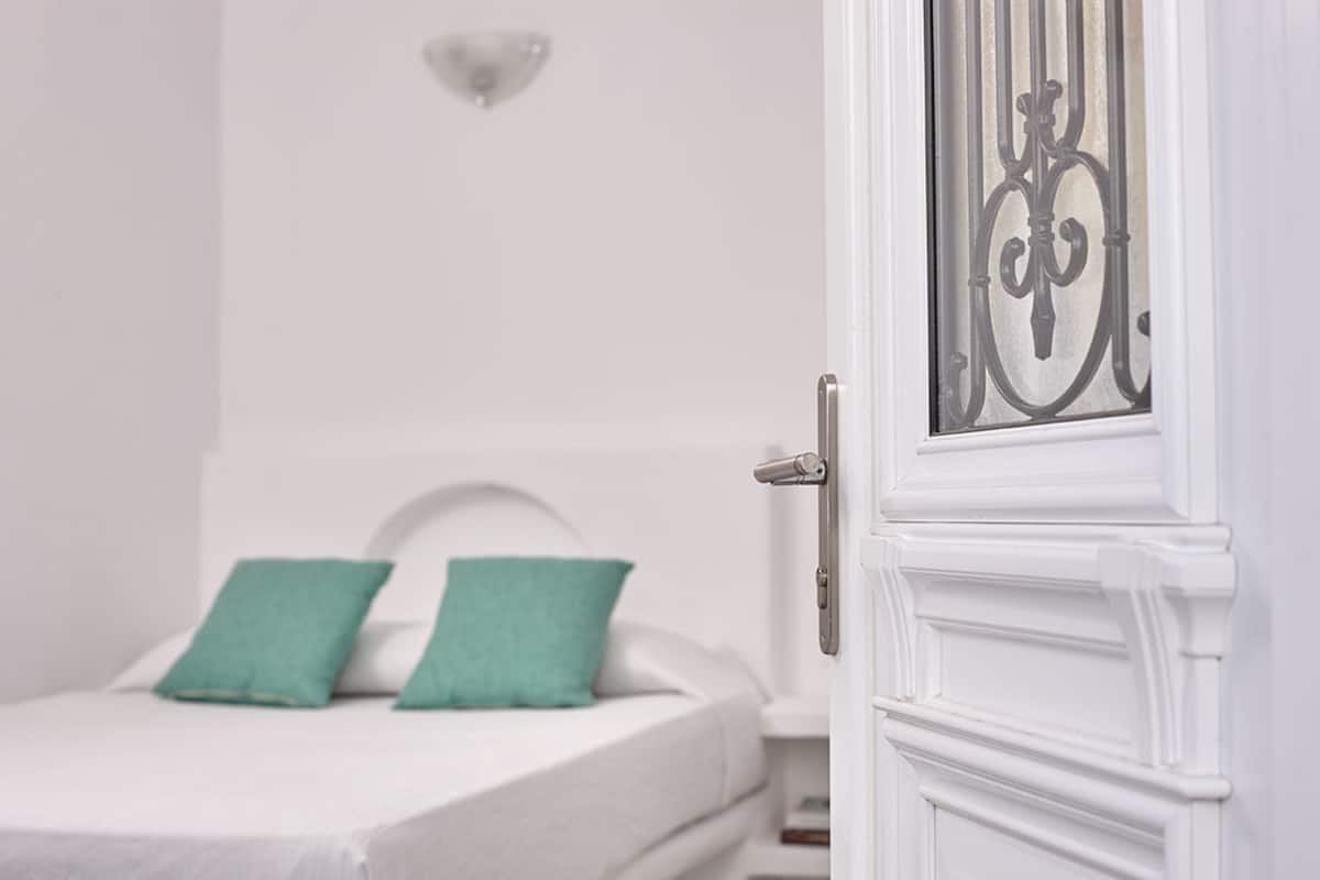A white door with a metal grille and a white wall with a light fixture.
