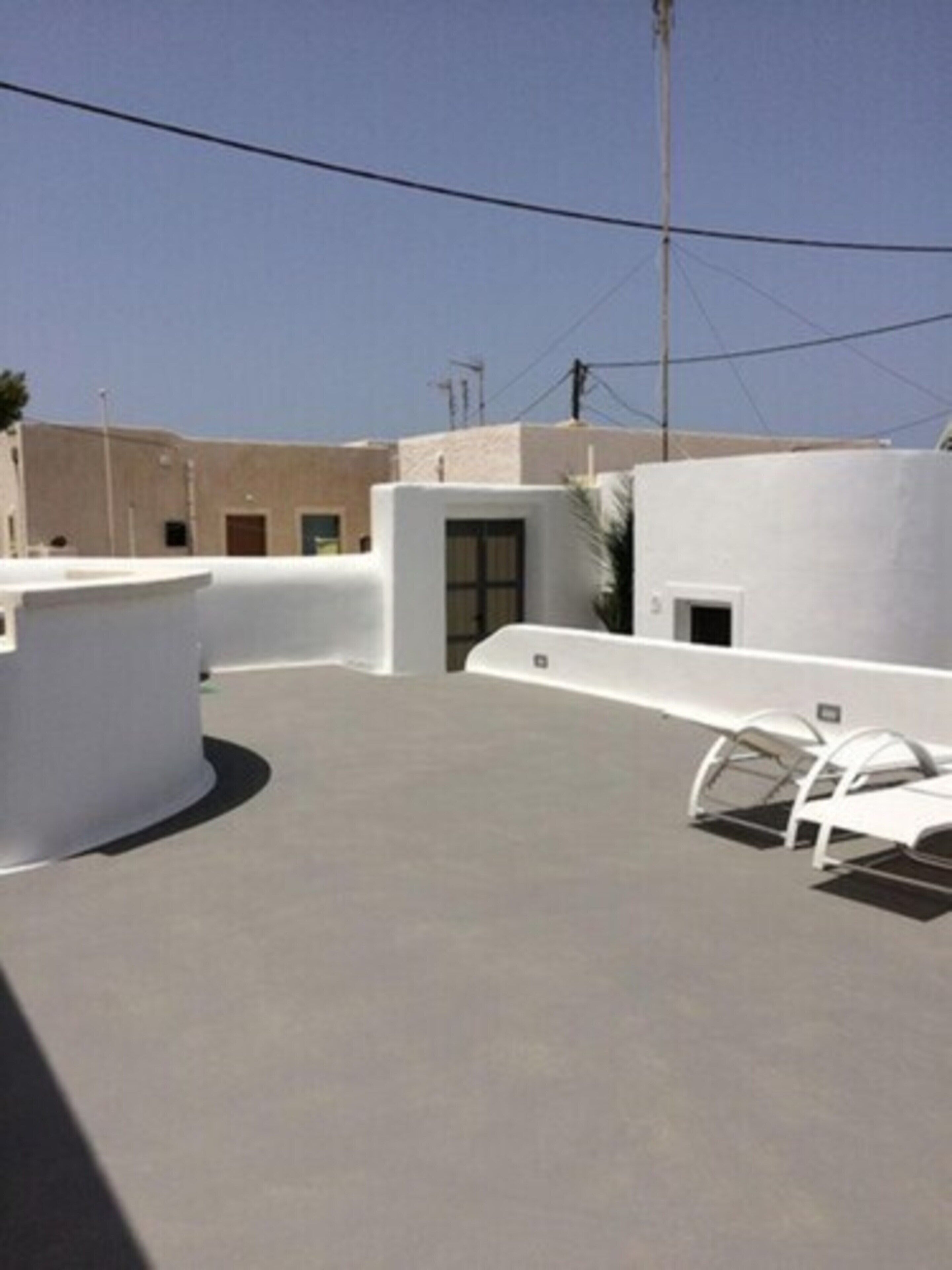 A rooftop with a flat surface, a covered seating area, and a building with a door and windows.