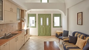 A spacious kitchen with a dining area, a sofa, and a small table. - Ayoba Santorini (Santorini)