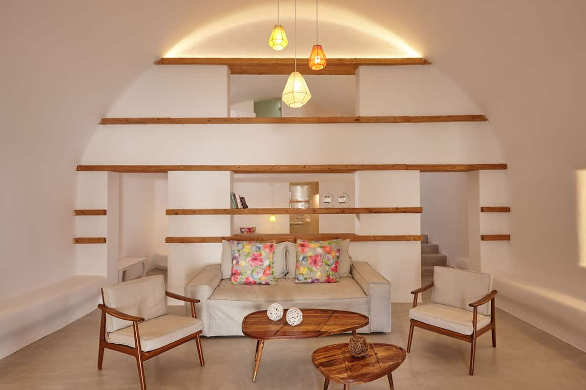A modern living room with a sofa, two armchairs, a coffee table, and pendant lighting.
