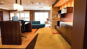 Un vestíbulo de hotel con mostrador de recepción, zona de estar y una pared de acento de piedra.