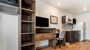 A modern kitchen with built-in appliances, a flat-screen TV, and a dining area with a chair.