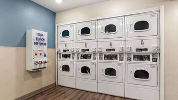 A laundry facility with multiple washing machines and a soap, bleach, and softener dispenser.