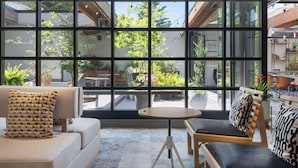 A modern living room with a large window, a sofa, a coffee table, and a bookshelf. - Freepoint Hotel Cambridge, Tapestry Collection by Hilton (Cambridge)