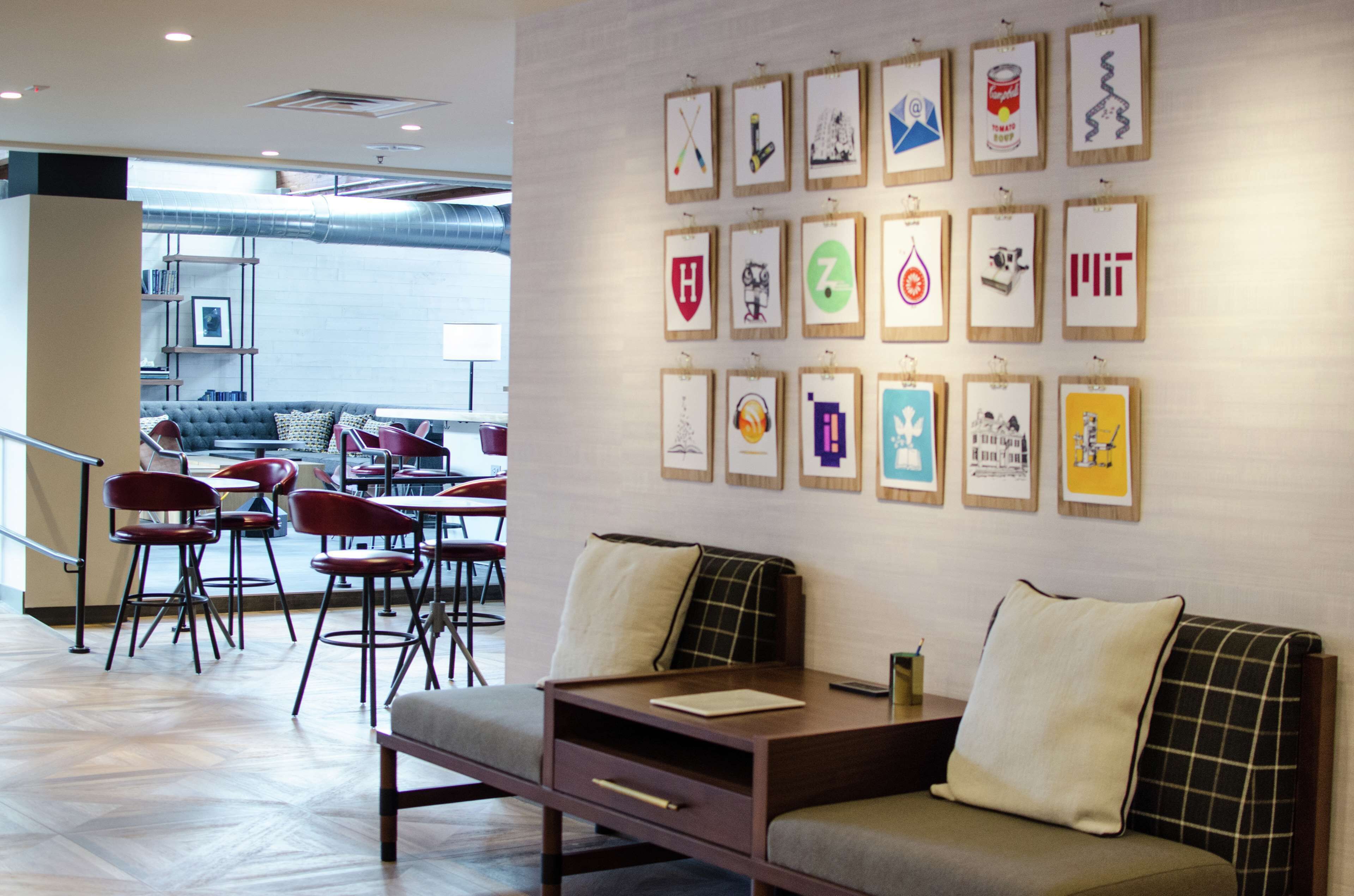 A modern interior with a sofa, chairs, and a wall of framed artwork.