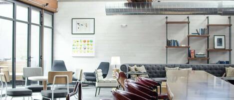 A modern conference room with a long table, several chairs, a sofa, and a bookshelf.