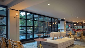 A modern lounge area with large windows, a bar, and seating arrangements including a sofa and chairs. - Freepoint Hotel Cambridge, Tapestry Collection by Hilton (Cambridge)