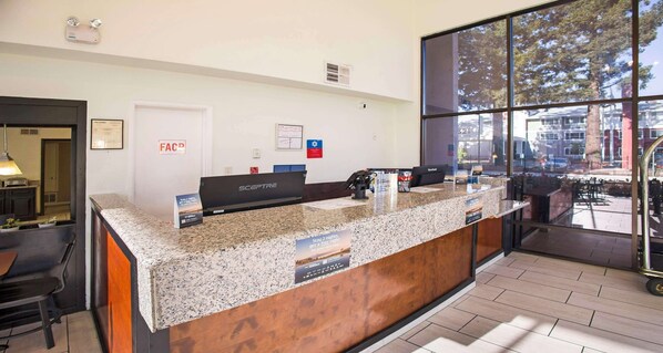A reception desk with a granite countertop, a computer, and a sign offering a stay 2 nights, get 1 free deal.