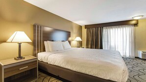 A hotel room with a large bed, two bedside tables with lamps, a headboard, and a window with curtains. - SureStay Plus Hotel by Best Western Sacramento North (Sacramento)