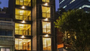 Een meerlaags gebouw met verlichte ramen en een balkon.