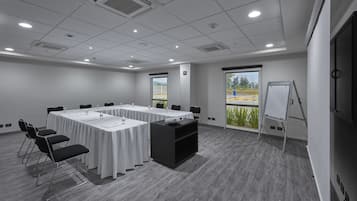 A conference room with a long table, chairs, a projector, and a whiteboard.