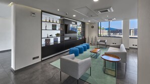 A modern lounge area with seating, a TV, and a view of the city. - Hotel Best Place Express (Zamora)