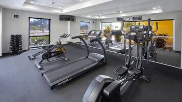 Un gimnasio con cintas de correr, elípticas y máquinas de pesas.