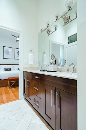 A modern bathroom with a large mirror, dual sinks, and a vanity with drawers. - The Guesthouse Hotel (Chicago)
