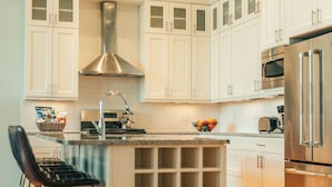 A modern kitchen with white cabinets, stainless steel appliances, and a wooden floor. - The Guesthouse Hotel (Chicago)