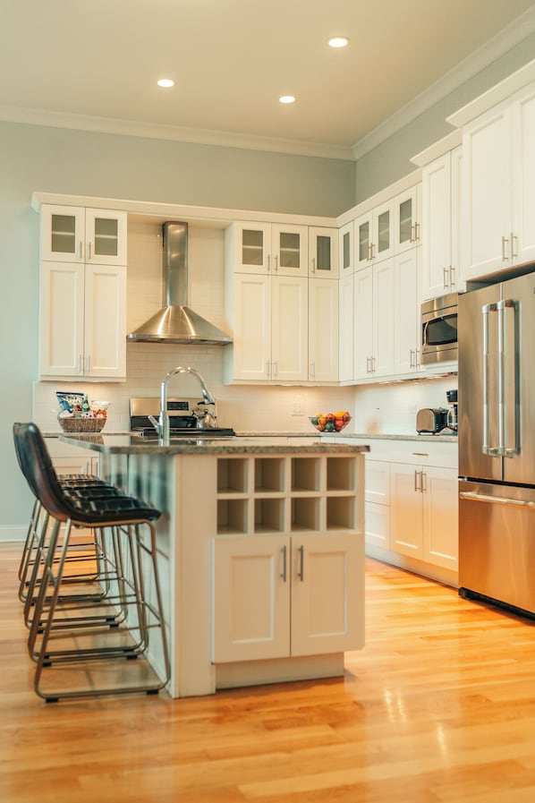 Una cocina moderna con armarios blancos, electrodomésticos de acero inoxidable y suelo de madera.
