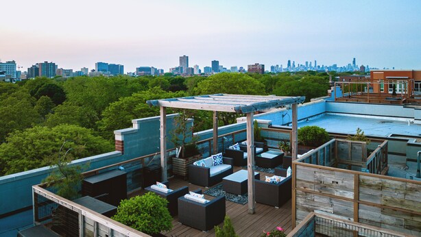 A rooftop patio with outdoor seating, a pergola, and a city skyline view. - The Guesthouse Hotel (Chicago)