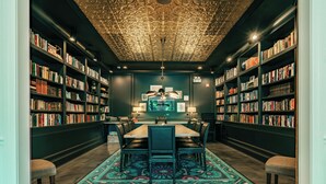 A library with a central table and chairs, surrounded by bookshelves. - The Guesthouse Hotel (Chicago)