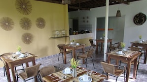 A dining area with multiple wooden tables and wicker chairs, arranged in a spacious layout. - Pousada das Acacias (São Miguel dos Milagres)