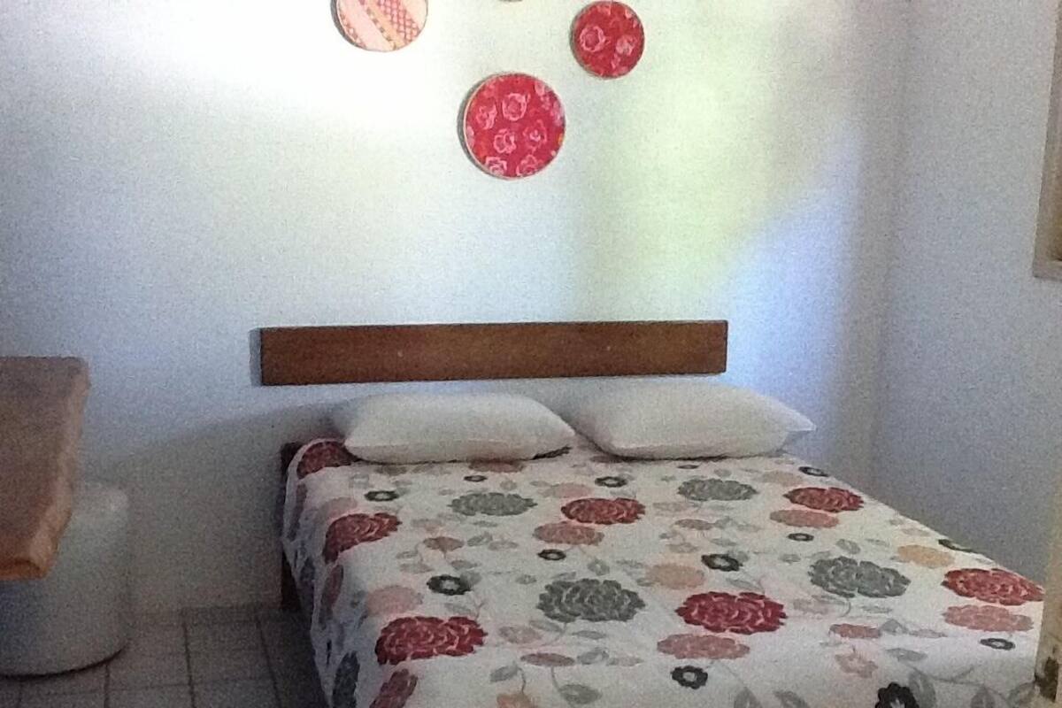 A bedroom with a bed, a wooden headboard, and a floral-patterned bedspread.