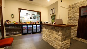 A snack bar area with a stone counter, seating, and a refrigerator stocked with beverages. - Gallery Hotel (Bibra Lake)