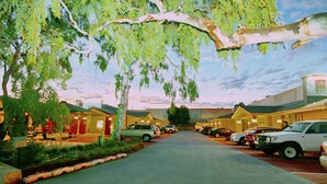 A street lined with parked cars and buildings with a clear sky above. - Gallery Hotel (Bibra Lake)