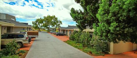 A residential street with houses, parked cars, and a sidewalk.