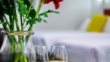 Eine Vase mit roten und weißen Blumen und zwei Gläsern Weißwein auf einem Tisch.