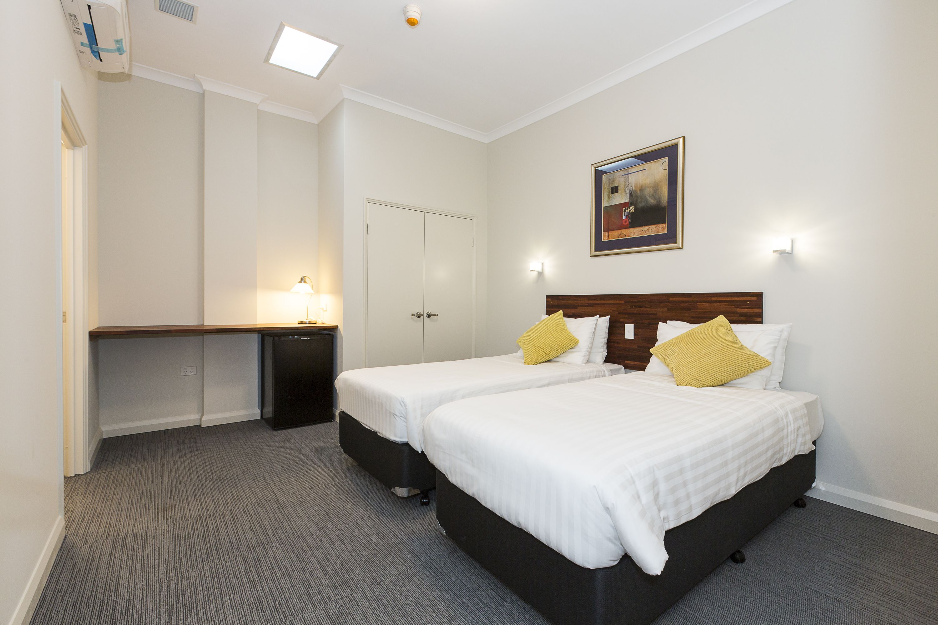 A hotel room with two beds, a desk, and a door.