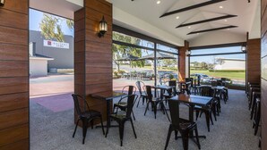 A restaurant with wooden paneling, black chairs, and tables. - Gallery Hotel (Bibra Lake)