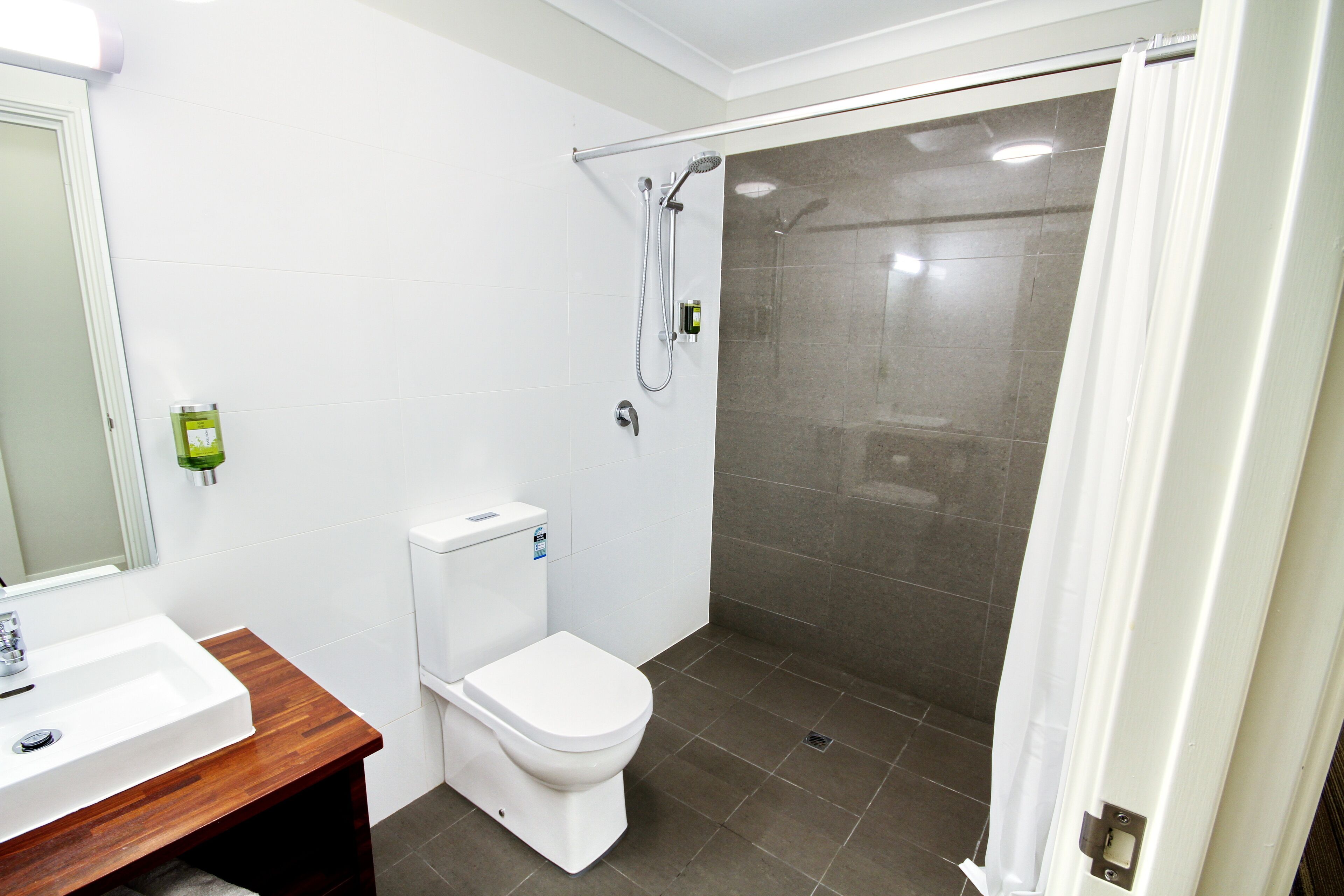 A bathroom with a white sink, toilet, and shower area.