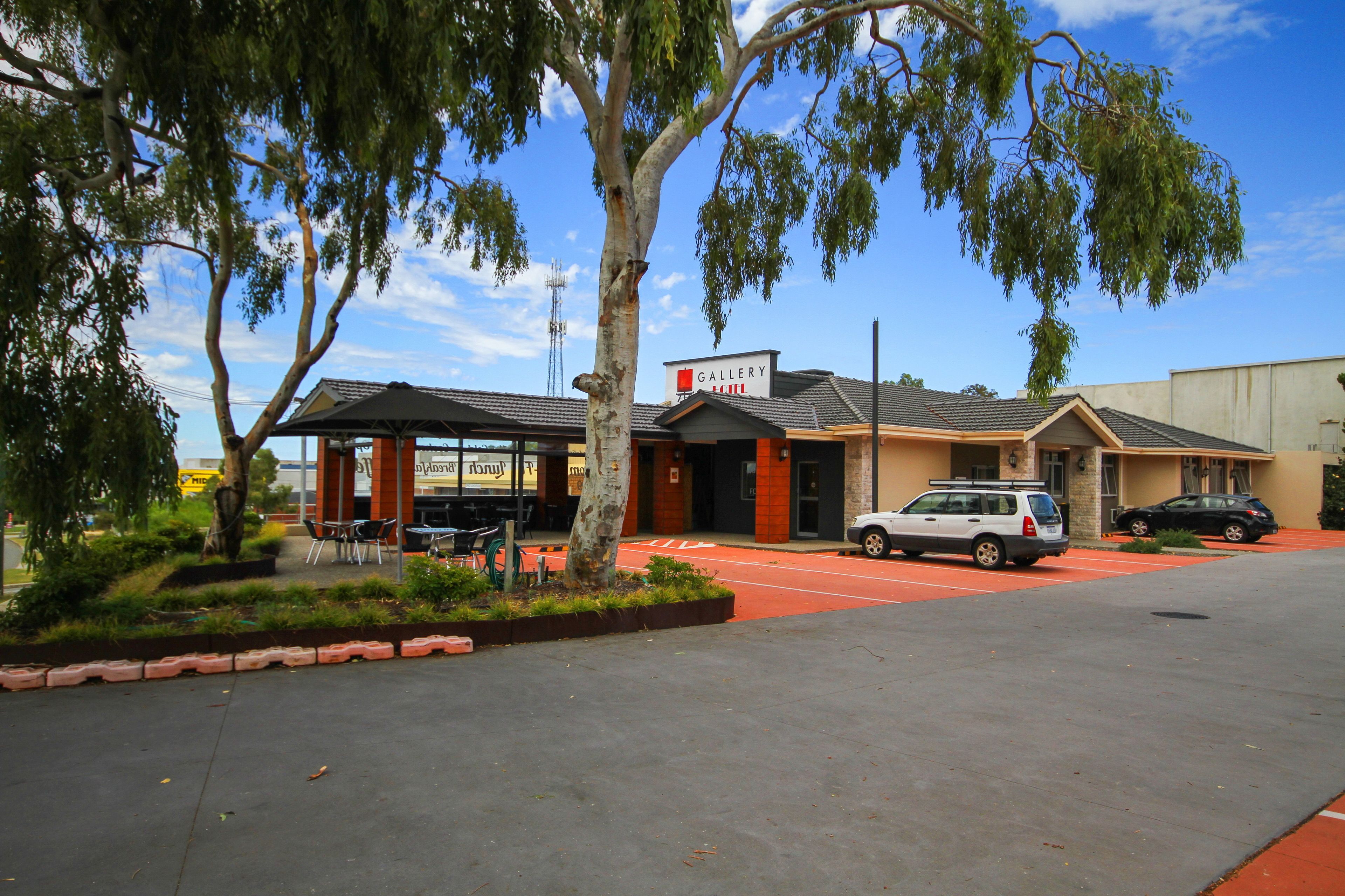 A building with a sign reading "GALLERY" and a parking lot with cars.