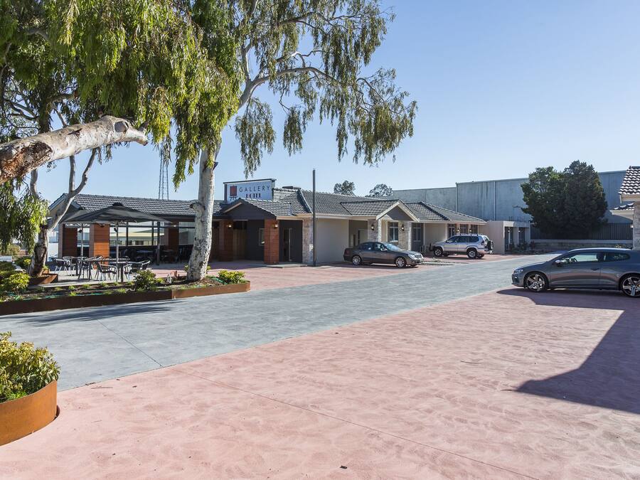 A street view of a commercial area with a row of buildings, including a gallery and a restaurant.