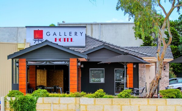 A hotel with a 'Gallery Hotel' sign, a coffee shop, and outdoor seating.