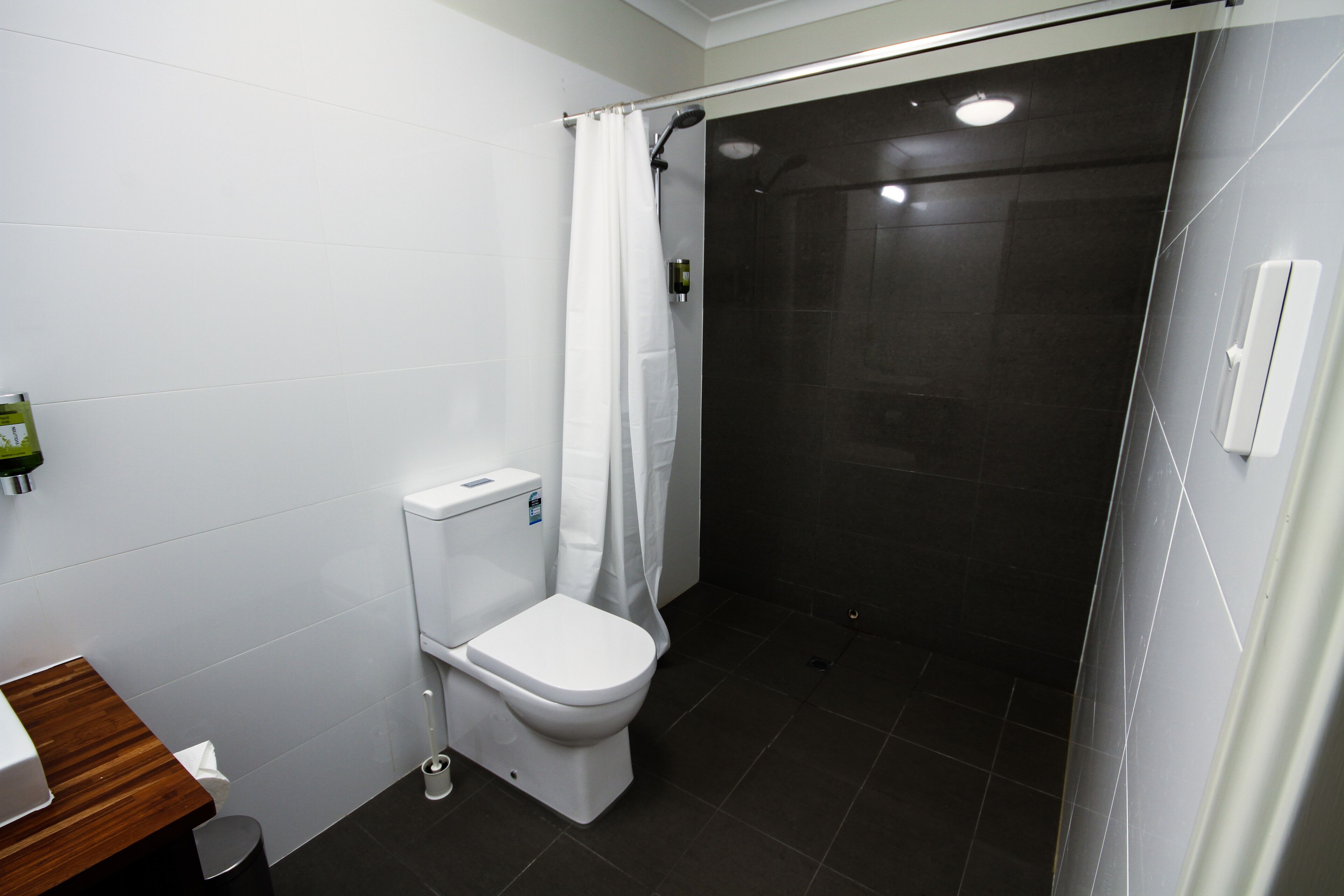 A modern bathroom with a toilet, shower, and sink.