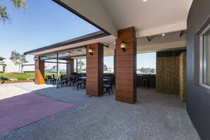 An outdoor patio area with tables and chairs, wooden pillars, and a view of the cityscape.