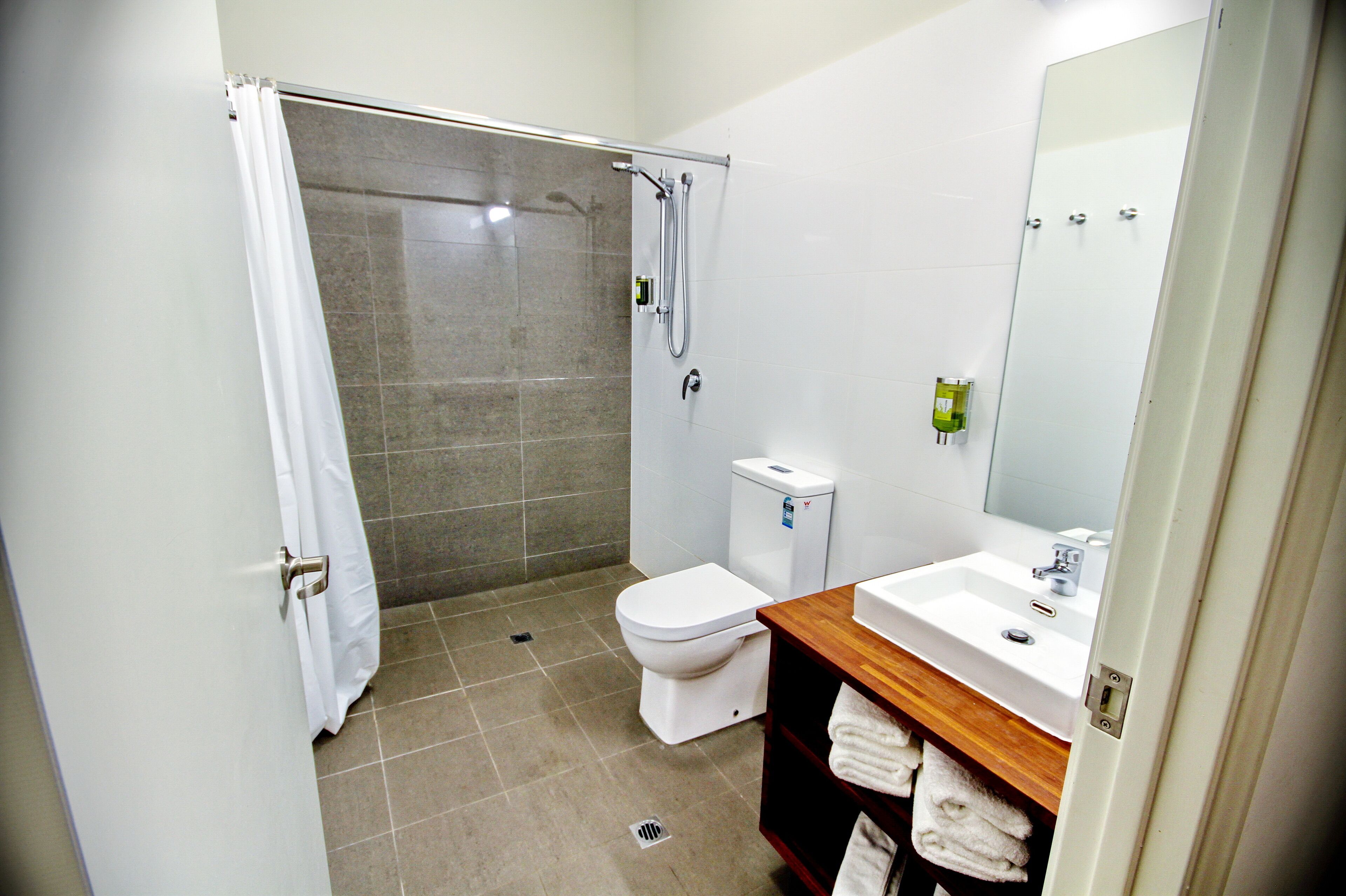 Un baño con ducha, inodoro, lavabo y espejo.