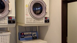 A laundry room with two stacked washing machines, a dryer, and a control panel. - Hotel LiVEMAX Kayabacho (Tokyo)