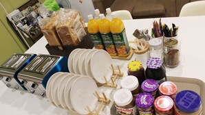 A table with various food items, including bread, juice, and condiments. - Orange Guesthouse - Hostel (Busan)