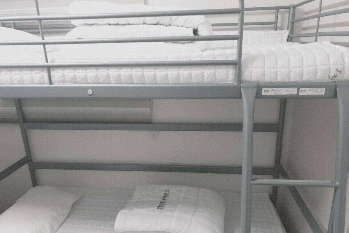 A bunk bed with a mattress and pillows, a metal ladder, and a folded blanket on the lower bunk.