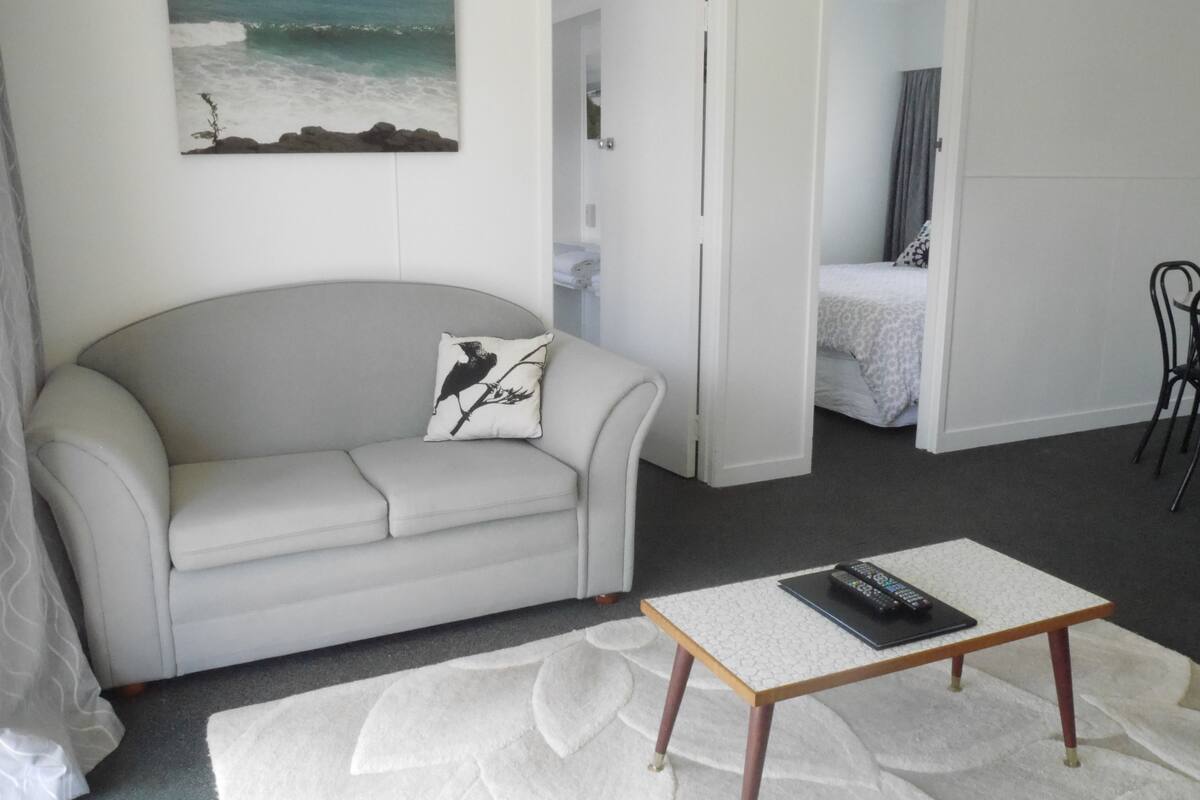 Una sala de estar moderna con un sofá, una mesa de centro y un cuadro de una playa.
