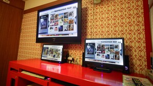 A room with a red desk, two laptops, and a television displaying a movie selection. - Castle Motel Iksan (Iksan)